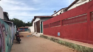 Une rue étroite, avec un mur rouge sur la droite et une fresque murale sur la gauche.