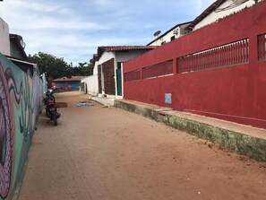 A narrow street with a red wall on the right and a mural on the left.
