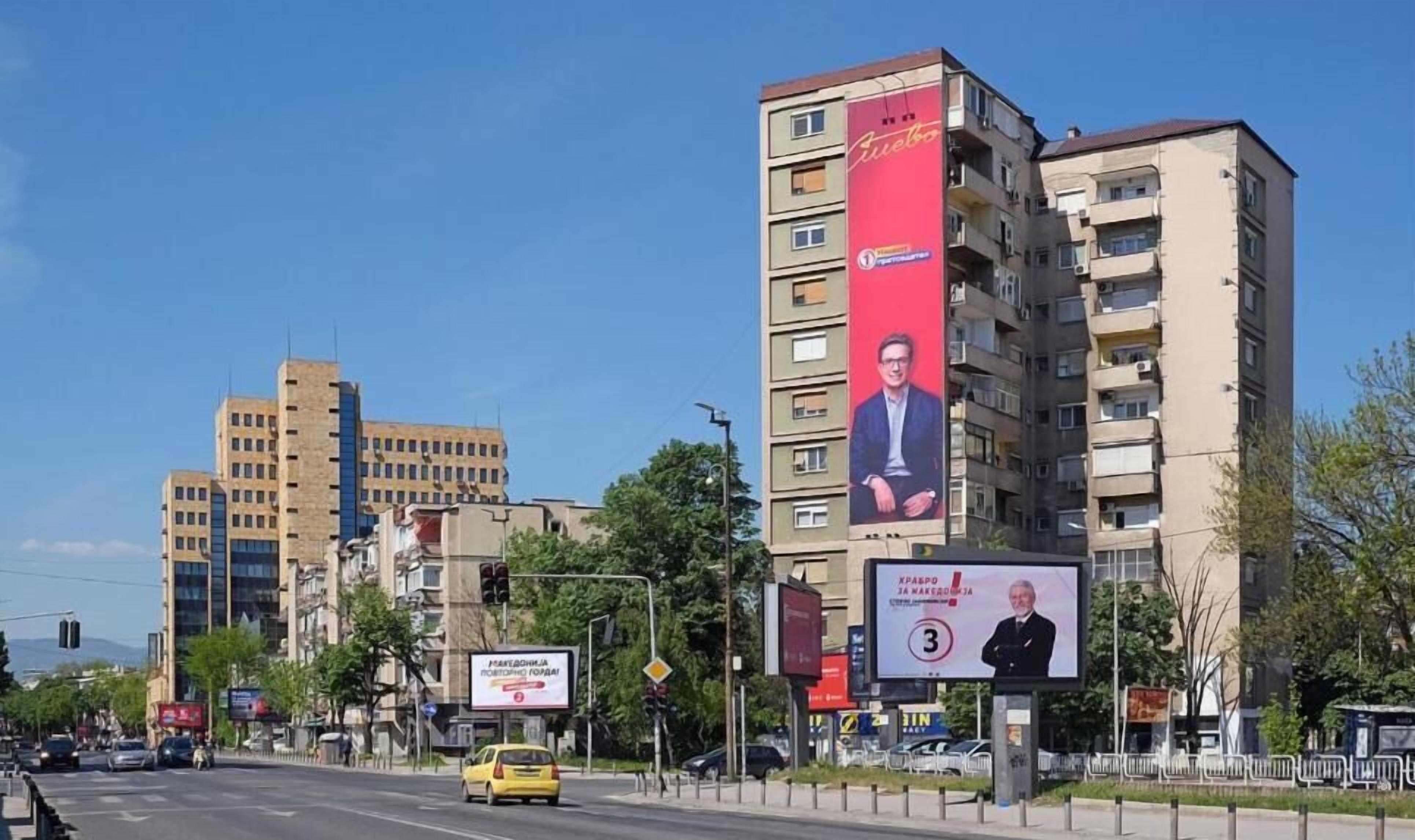 Een meerhoog gebouw met een opvallende reclamebord waarop een man staat.