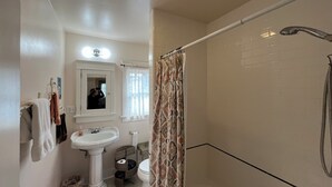 A bathroom with a pedestal sink, a mirror, a shower with a curtain, and a toilet. - Cozy 1-bedroom house in peaceful Monrovia with AC. Walk to historic Myrtle Ave. (Monrovia)