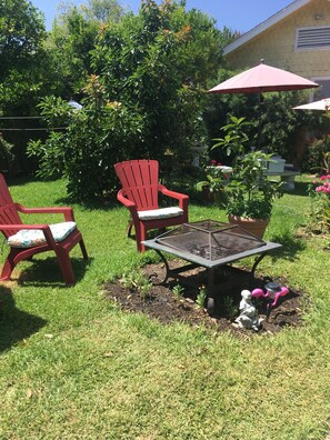 A garden area with two red chairs, a metal table, and a potted plant. - Cozy 1-bedroom house in peaceful Monrovia with AC. Walk to historic Myrtle Ave. (Monrovia)