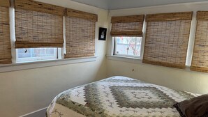 A bedroom with a bed, two windows with blinds, and a view of the outside. - Cozy 1-bedroom house in peaceful Monrovia with AC. Walk to historic Myrtle Ave. (Monrovia)