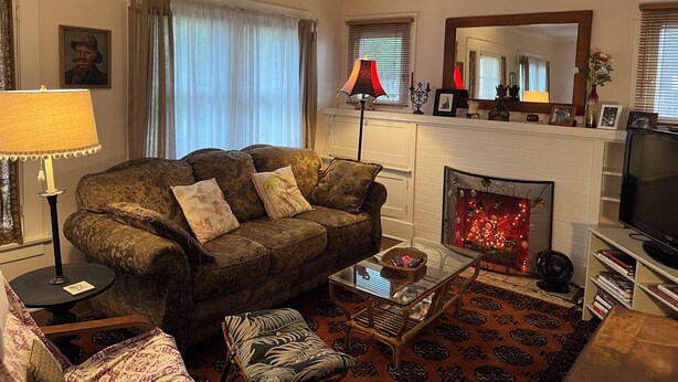 A living room with a sofa, a glass coffee table, a fireplace, and a television. - Cozy 1-bedroom house in peaceful Monrovia with AC. Walk to historic Myrtle Ave. (Monrovia)