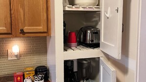 Een keuken met houten kastjes, een aanrecht met koffiezetapparaat, waterkoker en theeservies.