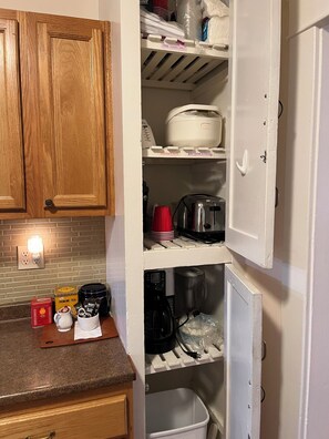 A kitchen with wooden cabinets, a countertop with a coffee maker, a kettle, and a tea set. - Cozy 1-bedroom house in peaceful Monrovia with AC. Walk to historic Myrtle Ave. (Monrovia)