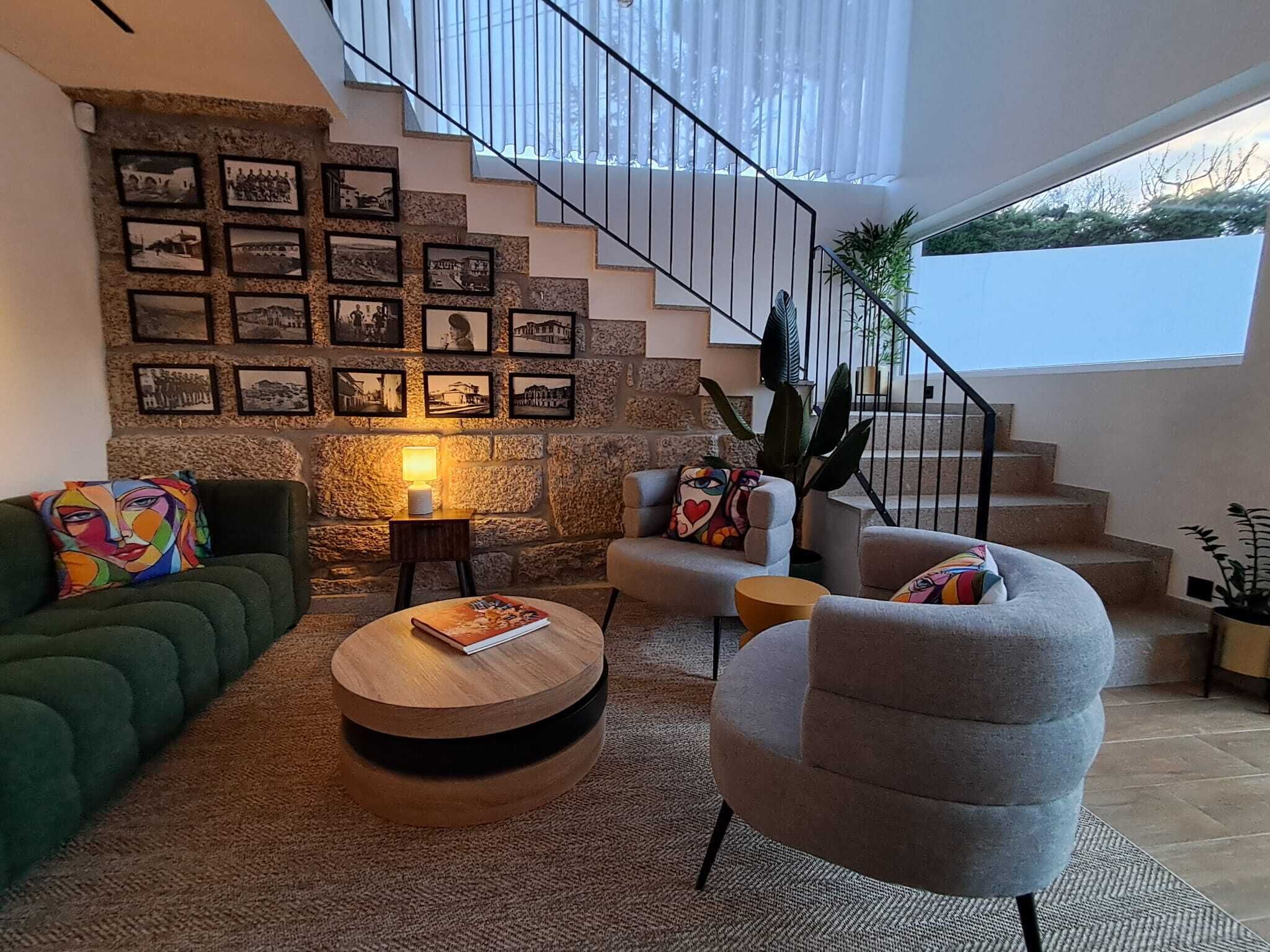 Una sala de estar moderna con una pared de piedra, una escalera y vistas al exterior.