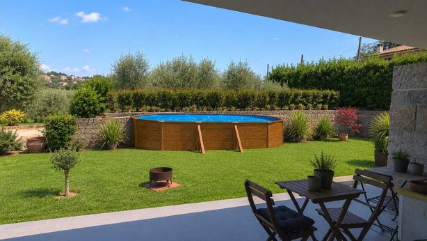 Un cortile con piscina in legno, un muro in pietra e un patio con tavolo e sedie.