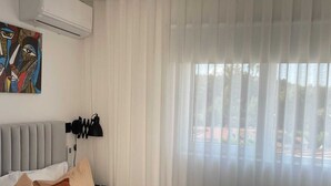Una camera d'albergo con un letto, un quadro, una lampada e una finestra con tende.