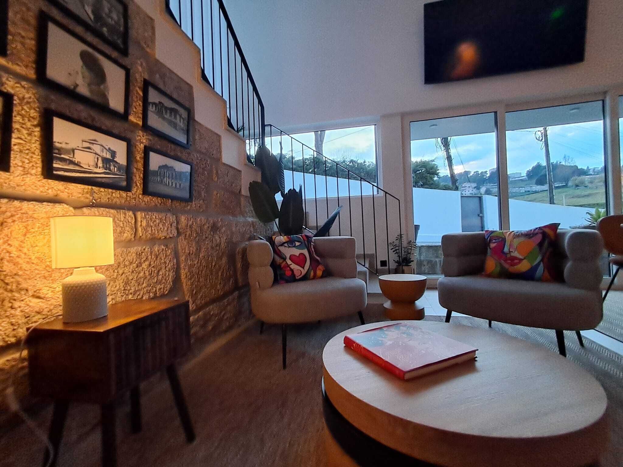 Un salon moderne avec un mur en pierre, un escalier et une vue sur une étendue d’eau.