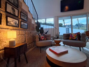 A modern living room with a stone wall, a staircase, and a view of a body of water.
