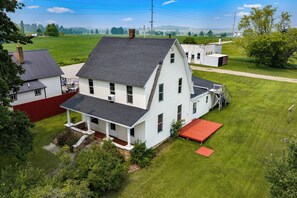 Uma casa de dois andares com varanda frontal e deck vermelho.