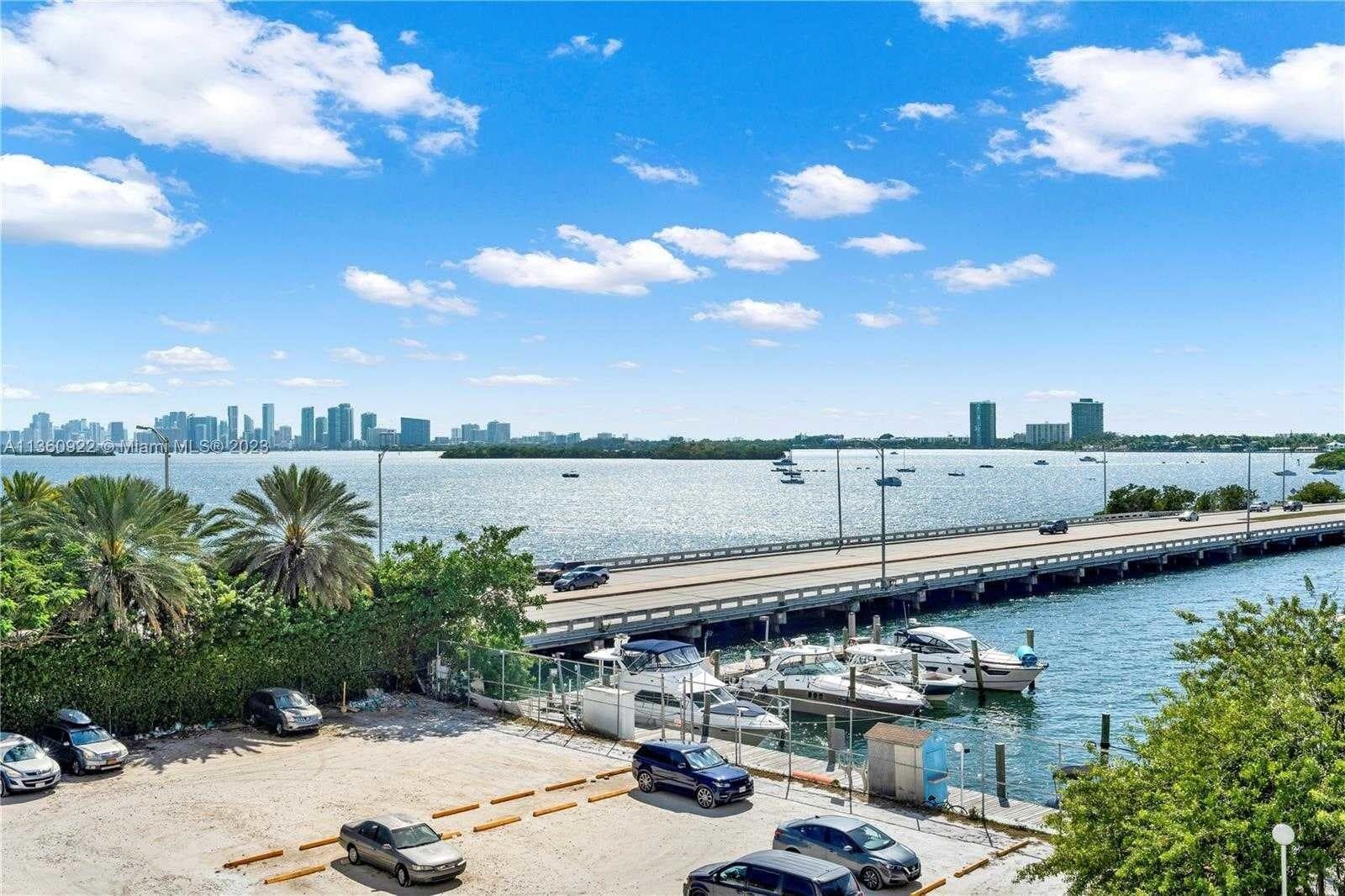 Elevated perspective of the surface parking lot, lower boat docks, and distant city skyline across the water.