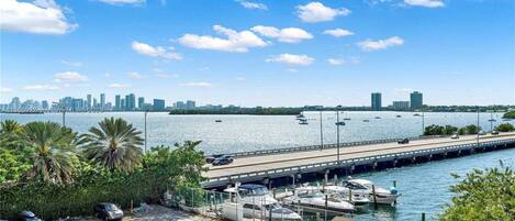 Elevated perspective of the surface parking lot, lower boat docks, and distant city skyline across the water.