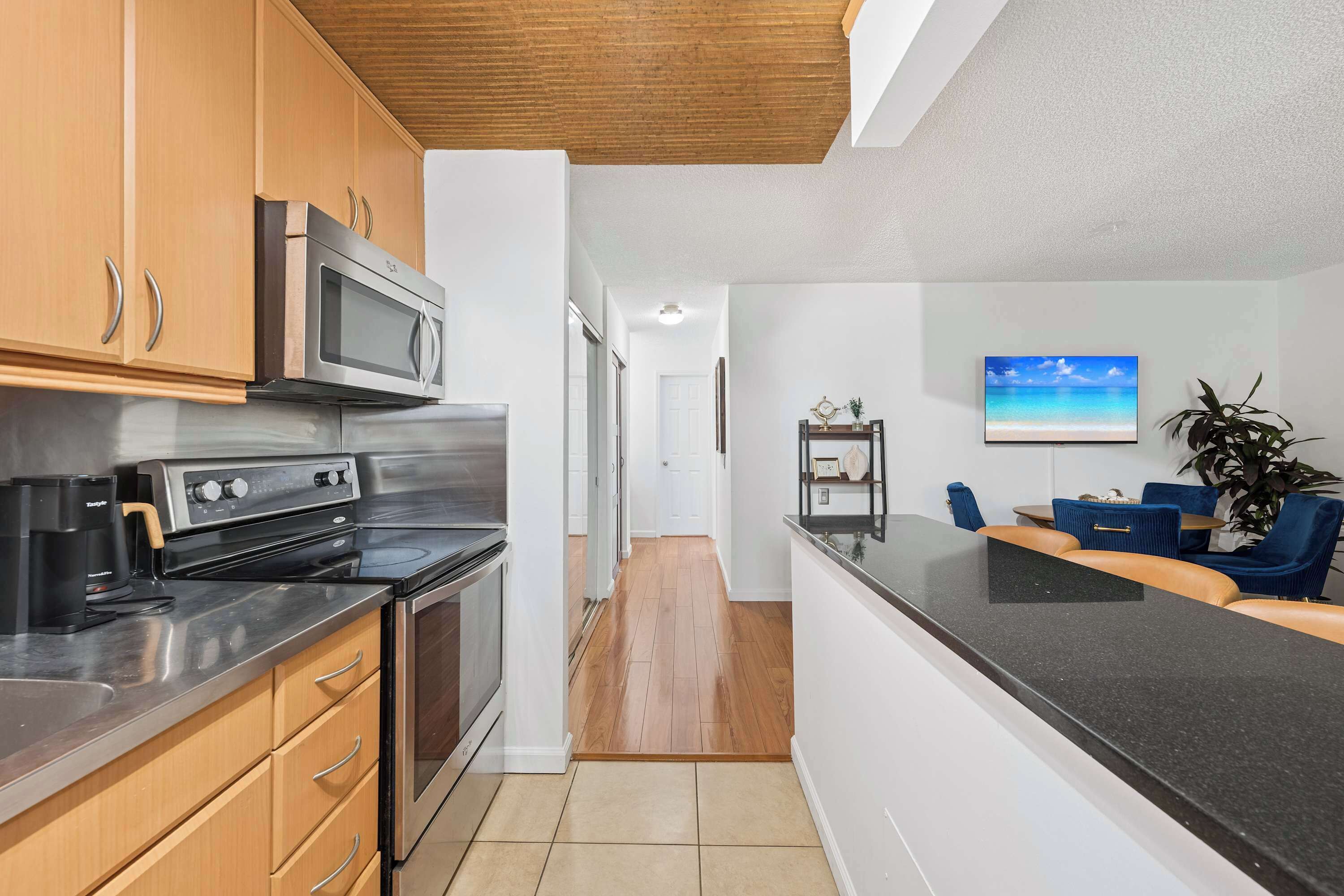 A modern kitchen with stainless steel appliances, wooden cabinets, and a black countertop.