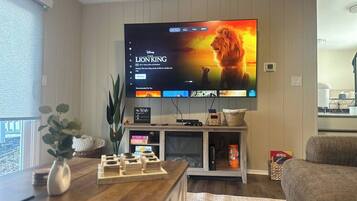 Ein Wohnzimmer mit einem Flachbildfernseher, der 'Der König der Löwen' zeigt, einem Holztisch, einer Pflanze und einem Sofa.