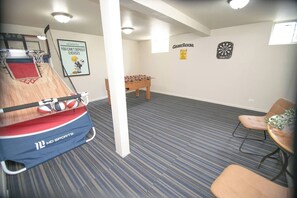 Una habitación con mesa de futbolín, dardos y aro de baloncesto.