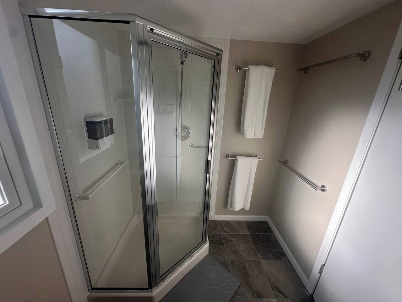 A glass-enclosed shower with a door, a towel rack, and a towel hanging on it.