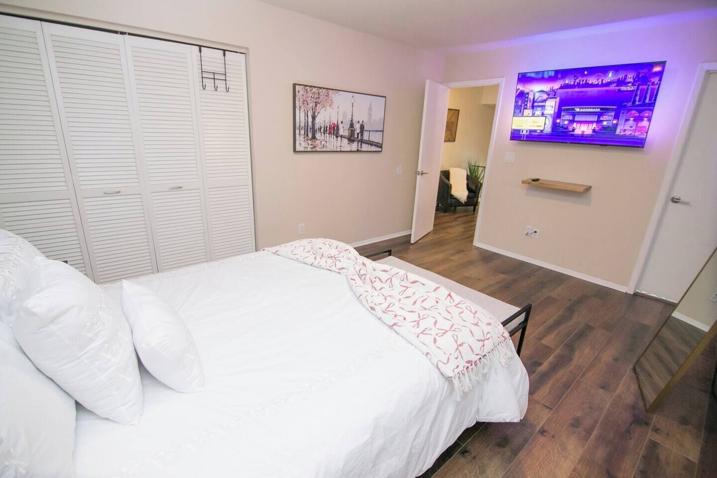 Une chambre à coucher comprenant un lit, une armoire, un téléviseur et une porte donnant sur une autre pièce.
