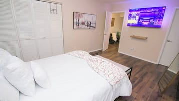 Une chambre à coucher comprenant un lit, une armoire, un téléviseur et une porte donnant sur une autre pièce.
