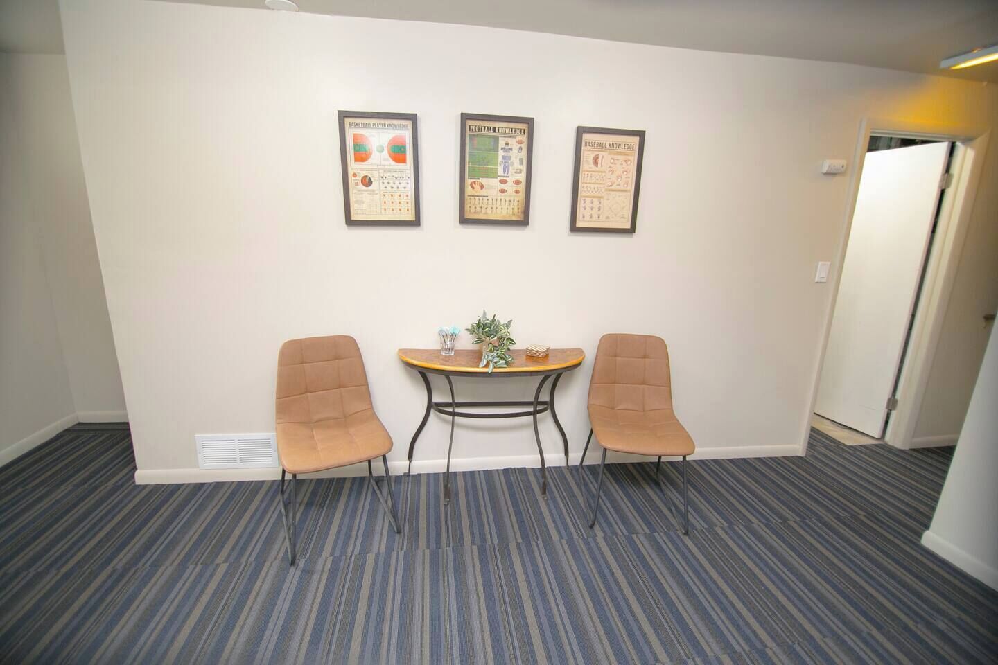Une salle de conférence avec une table, deux chaises et trois affiches encadrées accrochées au mur.
