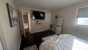 Une chambre à coucher avec un lit, une télévision, un miroir et une fenêtre.