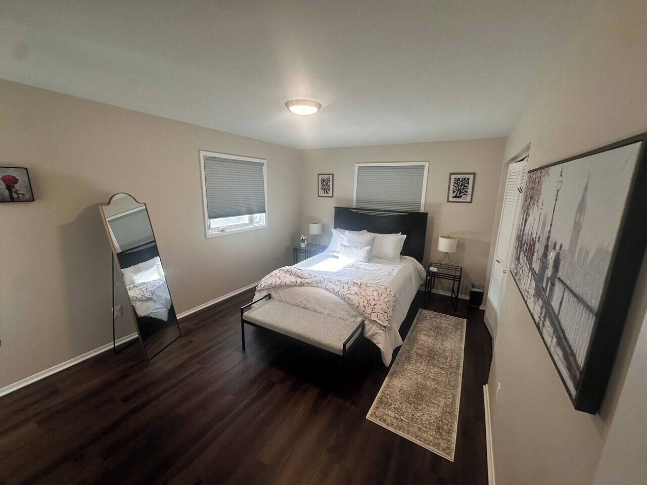 A bedroom with a bed, bedside tables, a nightstand, a mirror, and a rug.