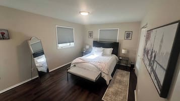 A bedroom with a bed, bedside tables, a nightstand, a mirror, and a rug.