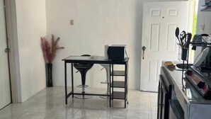 Een keuken met een eettafel, stoelen, een koelkast en een deur.