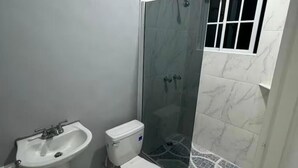 Een badkamer met toilet, wastafel en douchecabine.