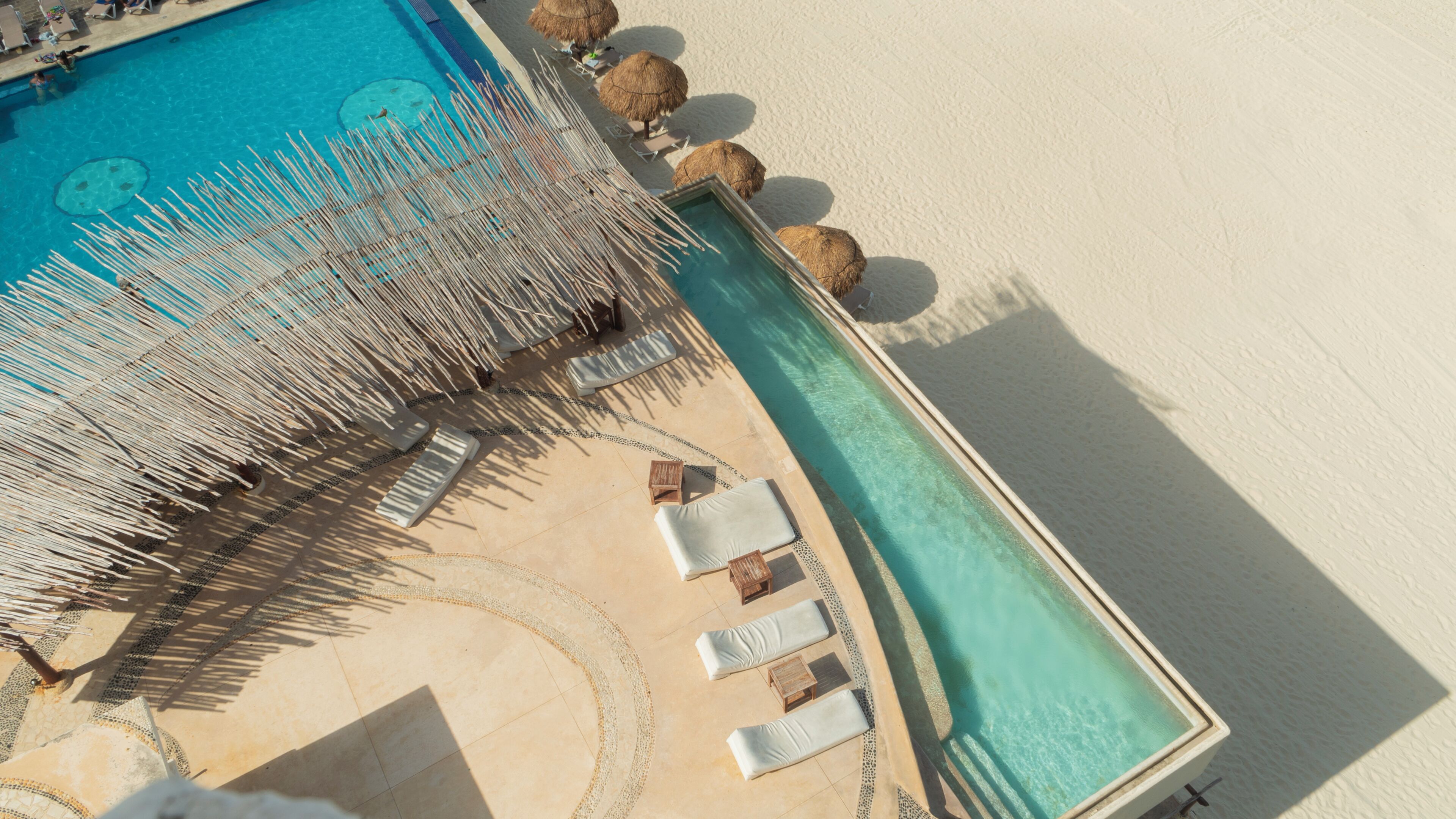 An aerial view of a pool area with lounge chairs and umbrellas.