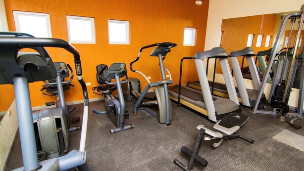 Uma academia com diversos equipamentos de exercícios, incluindo esteiras, elípticos e aparelhos de musculação.