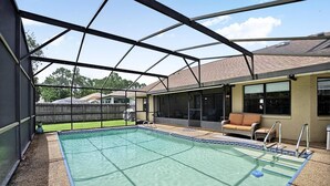 Ein überdachter Außenpool mit Terrassenbereich, einer Liege und einem Grill.