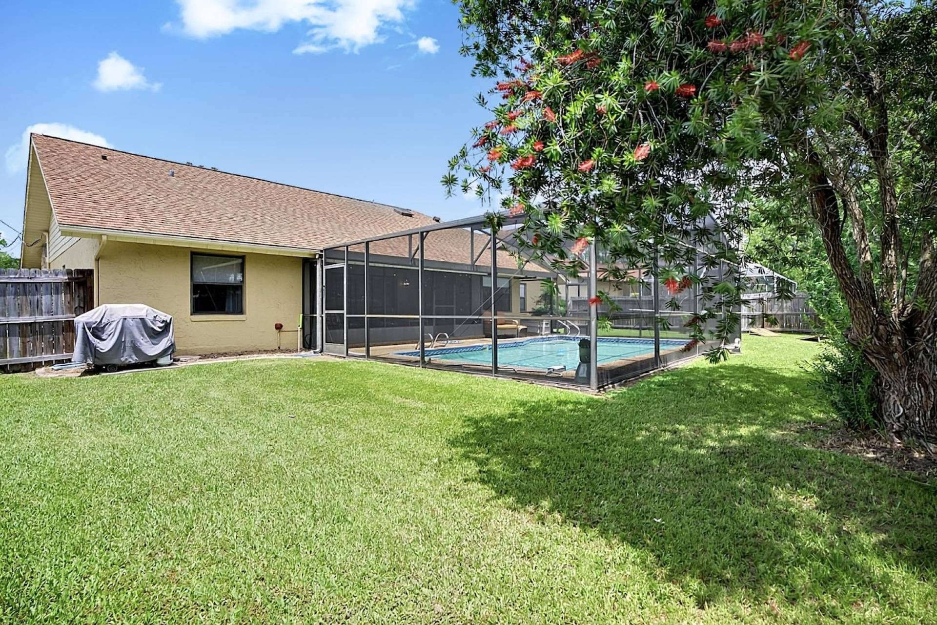 A house with a screened-in porch, a swimming pool, and a covered grill.