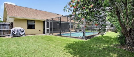 A house with a screened-in porch, a swimming pool, and a covered grill.