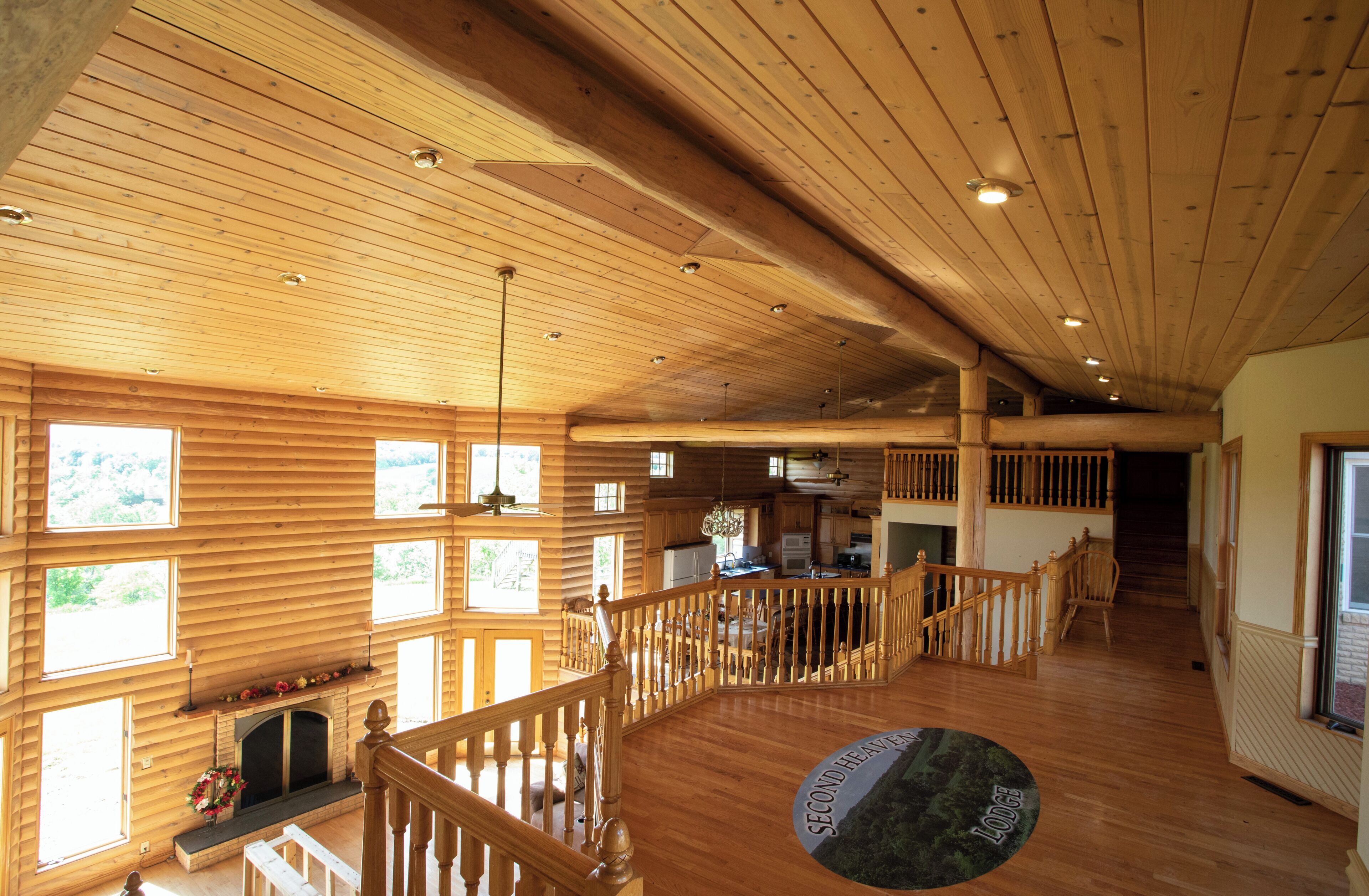 A spacious lodge interior with wooden floors, a fireplace, and multiple windows.