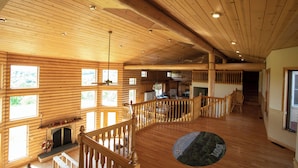 Un'ampia sala interna con pavimenti in legno, un camino e numerose finestre.