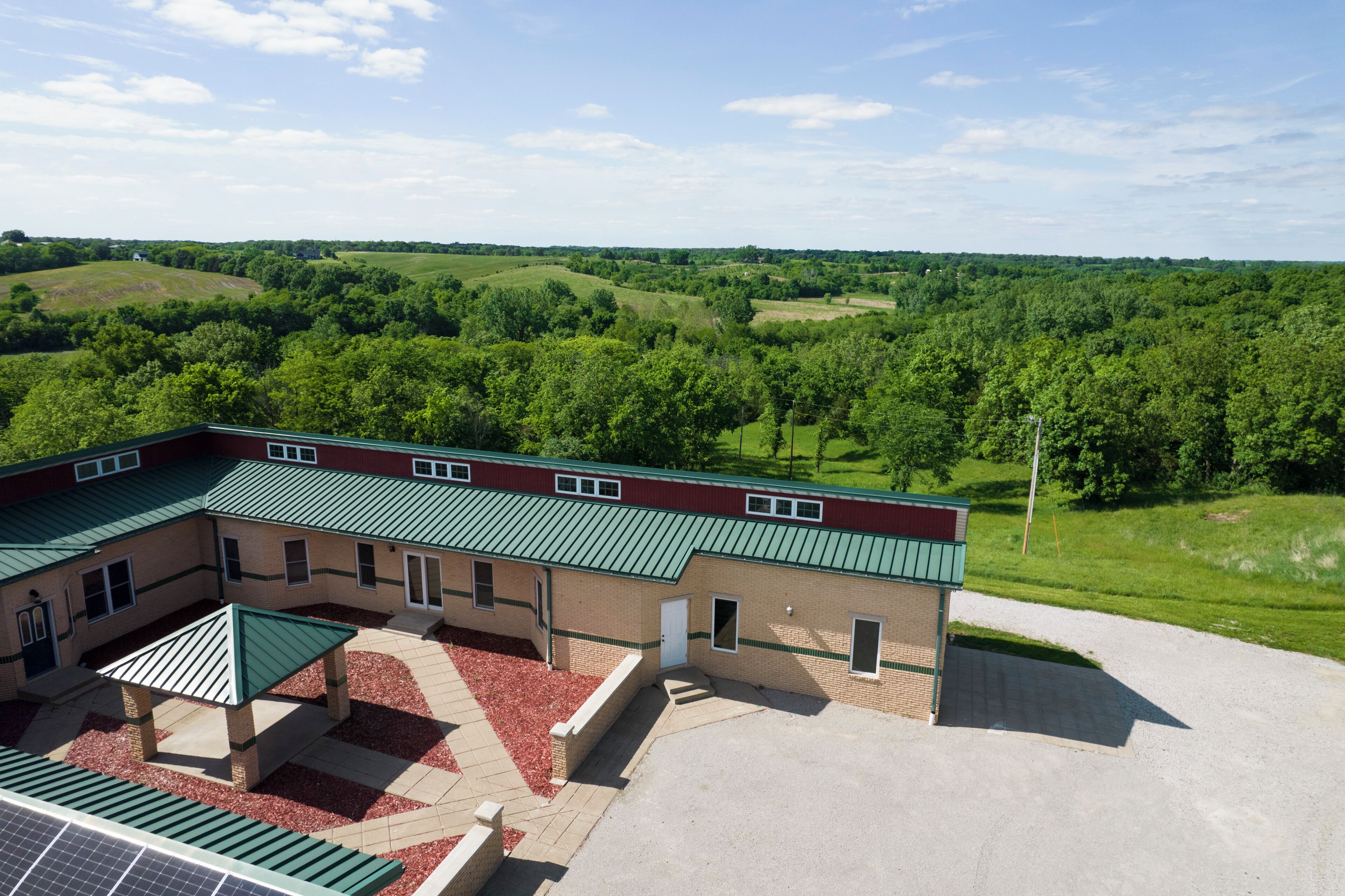 A building with a green roof, multiple entry points, and a paved area with solar panels.