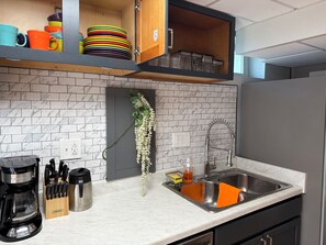 A kitchen with a marble backsplash, a stainless steel sink, and a coffee maker.