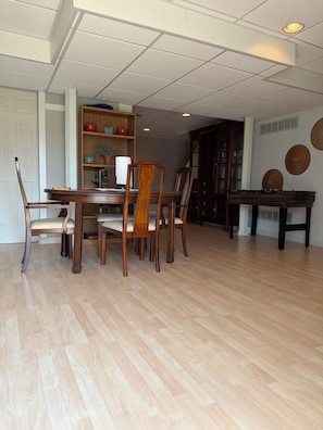 Un coin repas avec une table et des chaises en bois, une bibliothèque et un mur décoré d’assiettes.
