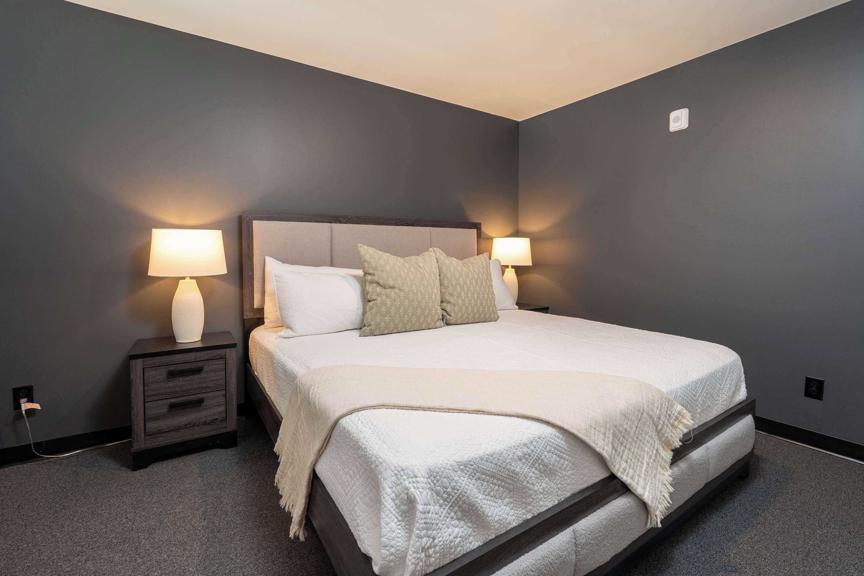 A bedroom with a bed, two bedside tables with lamps, and a wall socket.