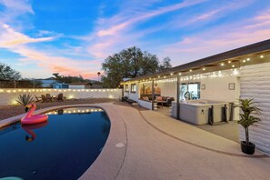 Ein Swimmingpool mit einem Flamingopflotter, einem Whirlpool und einer überdachten Terrasse mit Lichterkette.