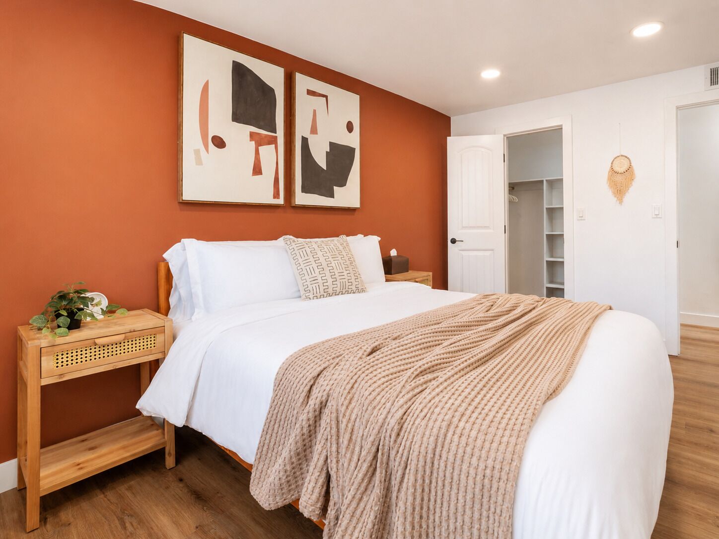 A bedroom with a bed, a nightstand, a wall-mounted shelf, and a door leading to a closet.