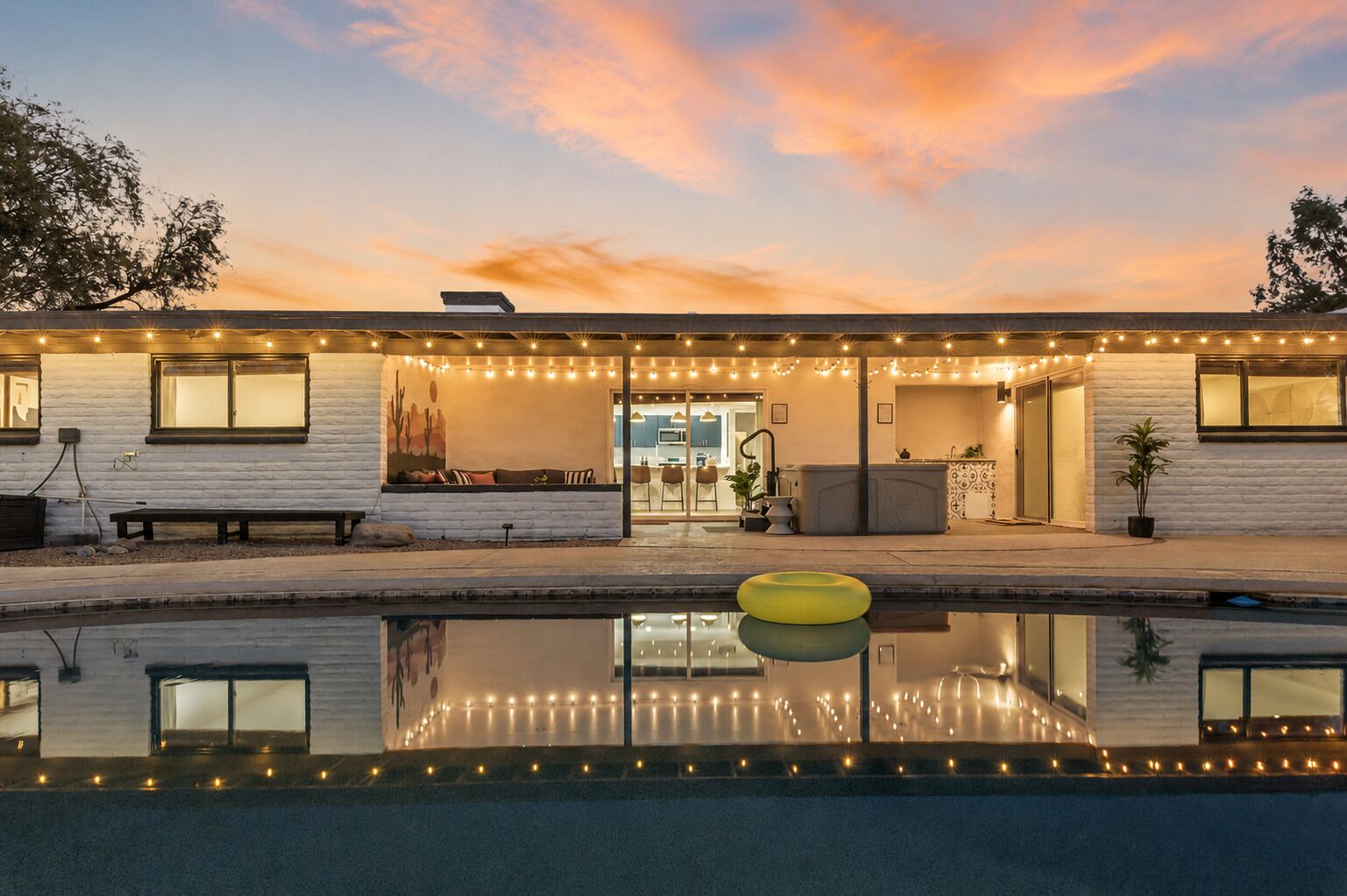 Una casa con piscina, luces colgantes y un mural con motivos desérticos.