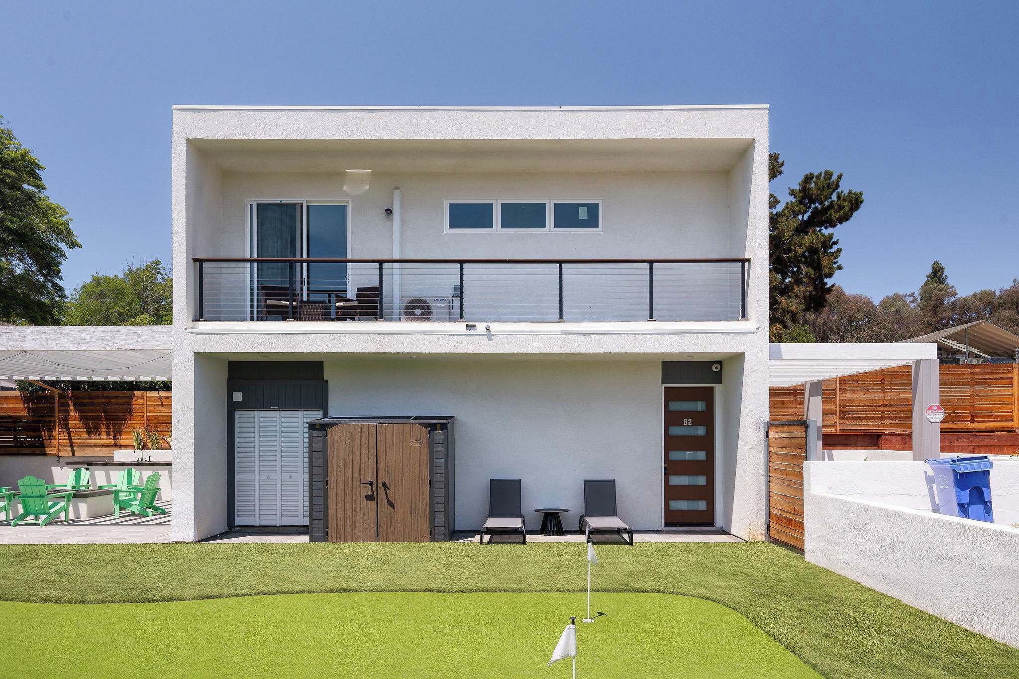 A two-story building with a balcony, a garage, and a well-maintained lawn.