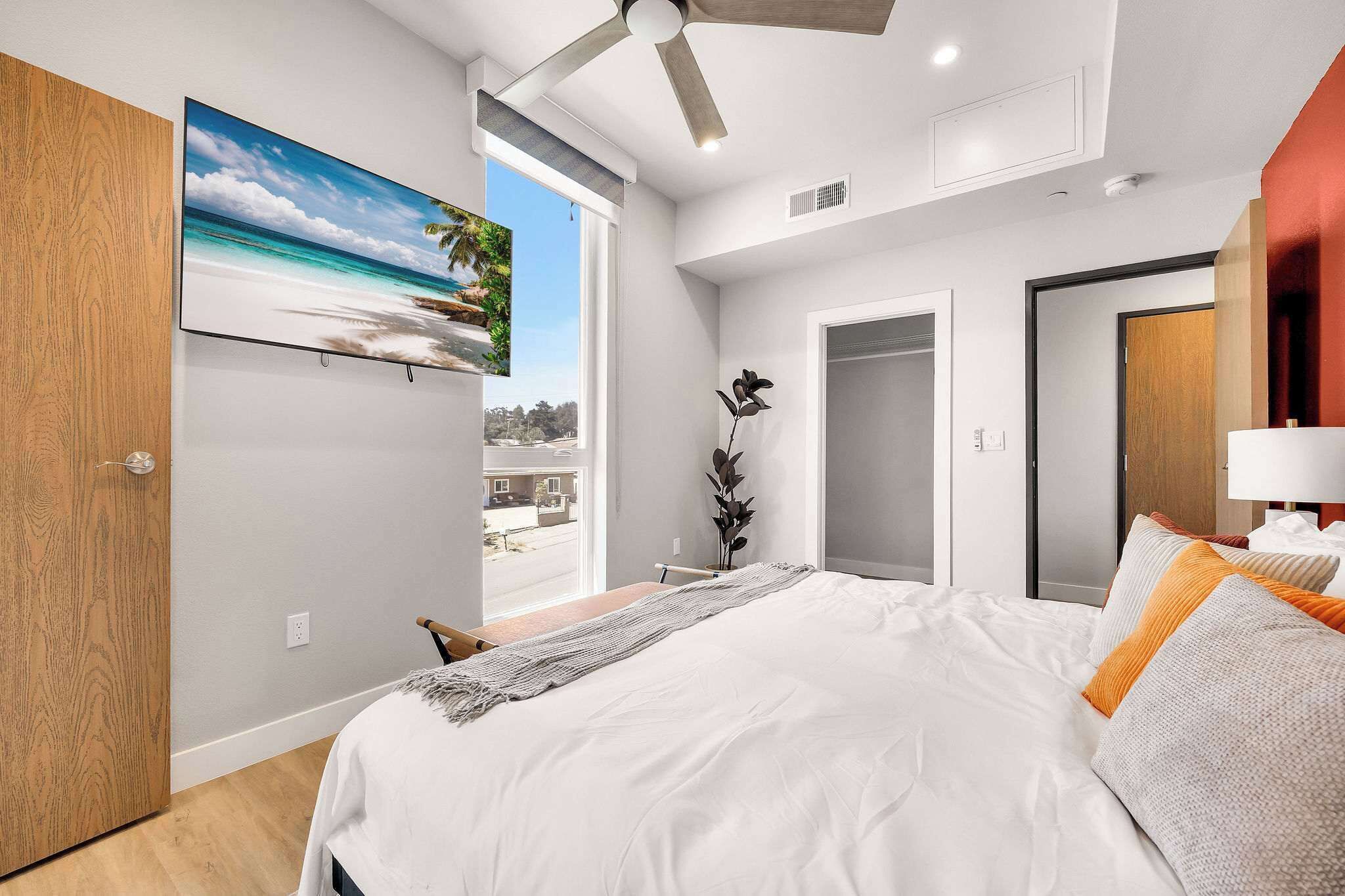 A bedroom with a bed, a painting, a ceiling fan, and a window.