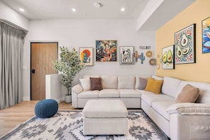 Una sala moderna con un sofá modular, un otoman azul y un tapete estampado.