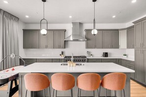 A modern kitchen with a central island, stainless steel appliances, and pendant lighting.