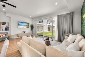 A modern living room with a sofa, a coffee table, and a large window with a view of a balcony.