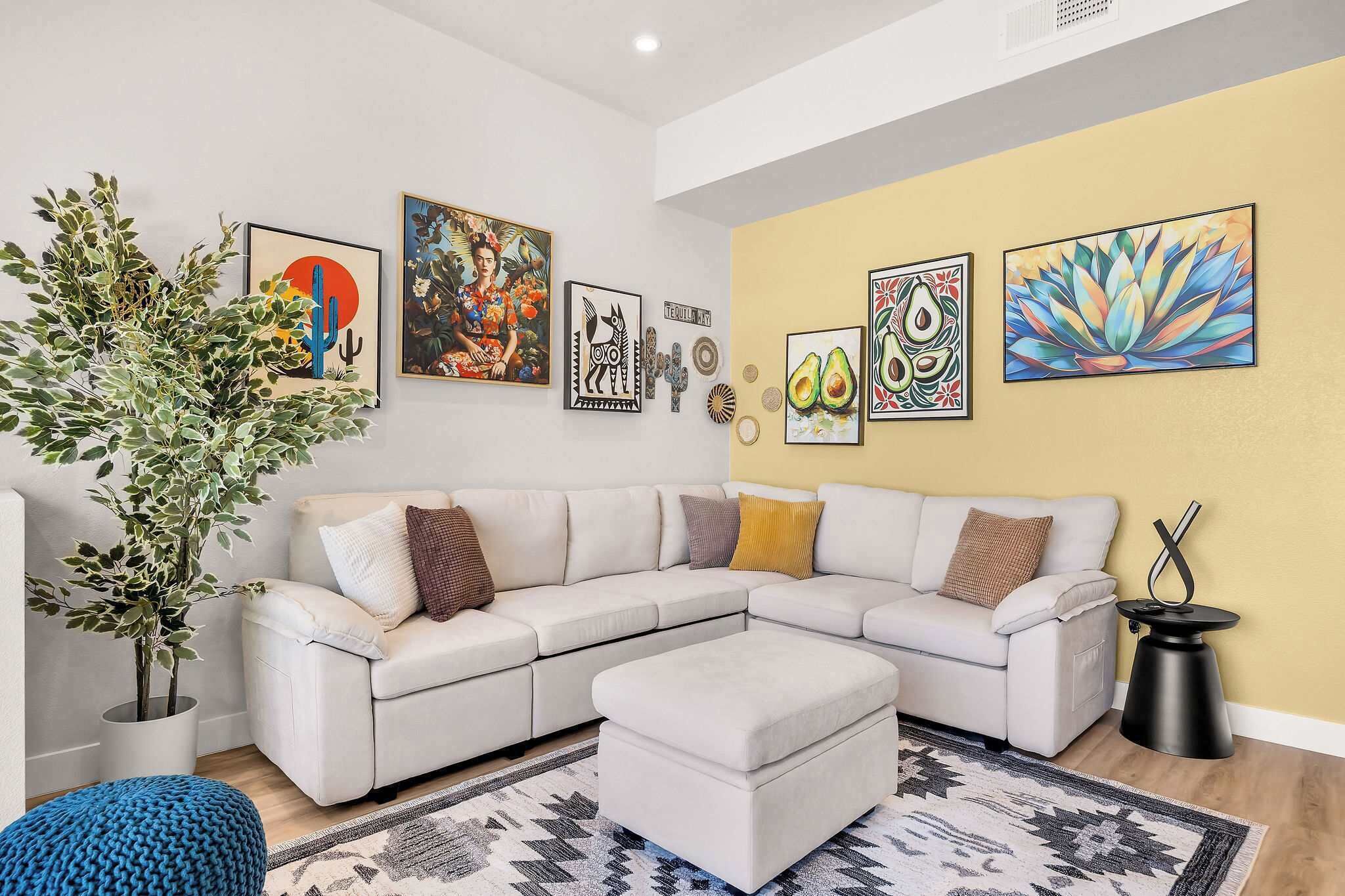 Una sala de estar moderna con un sofá modular blanco, una planta grande en maceta y varias obras de arte en la pared.