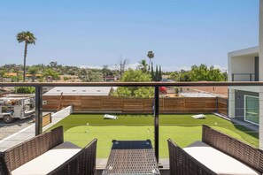 Una terraza con vistas a una zona residencial, una cerca de madera y un pequeño césped.